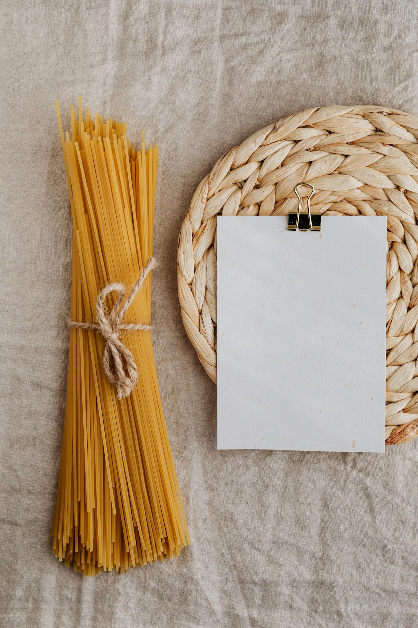 Composition with empty clipboard and spaghetti on kitchen table
