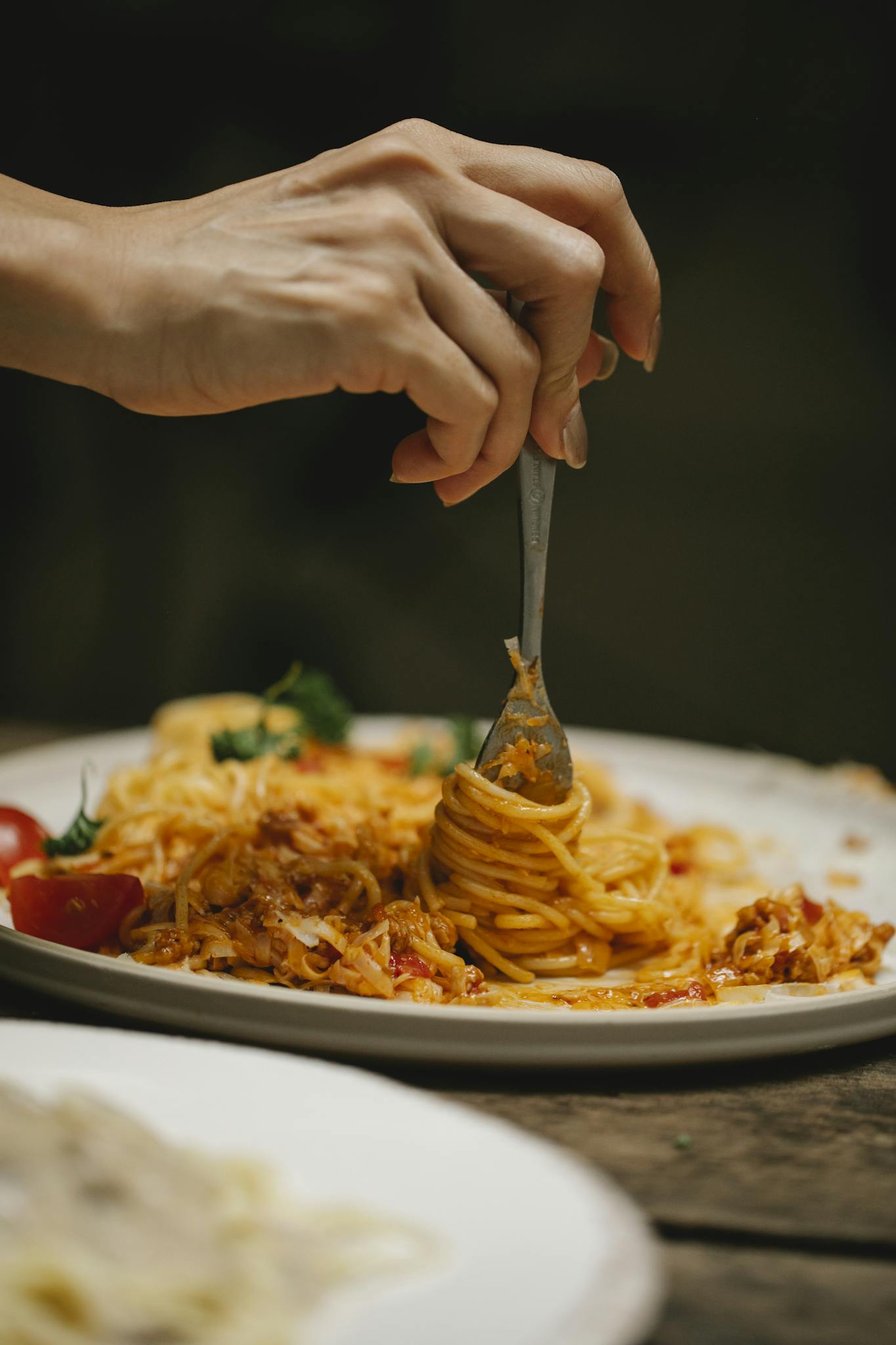 Crop unrecognizable woman with fork enjoying yummy Bolognese pasta